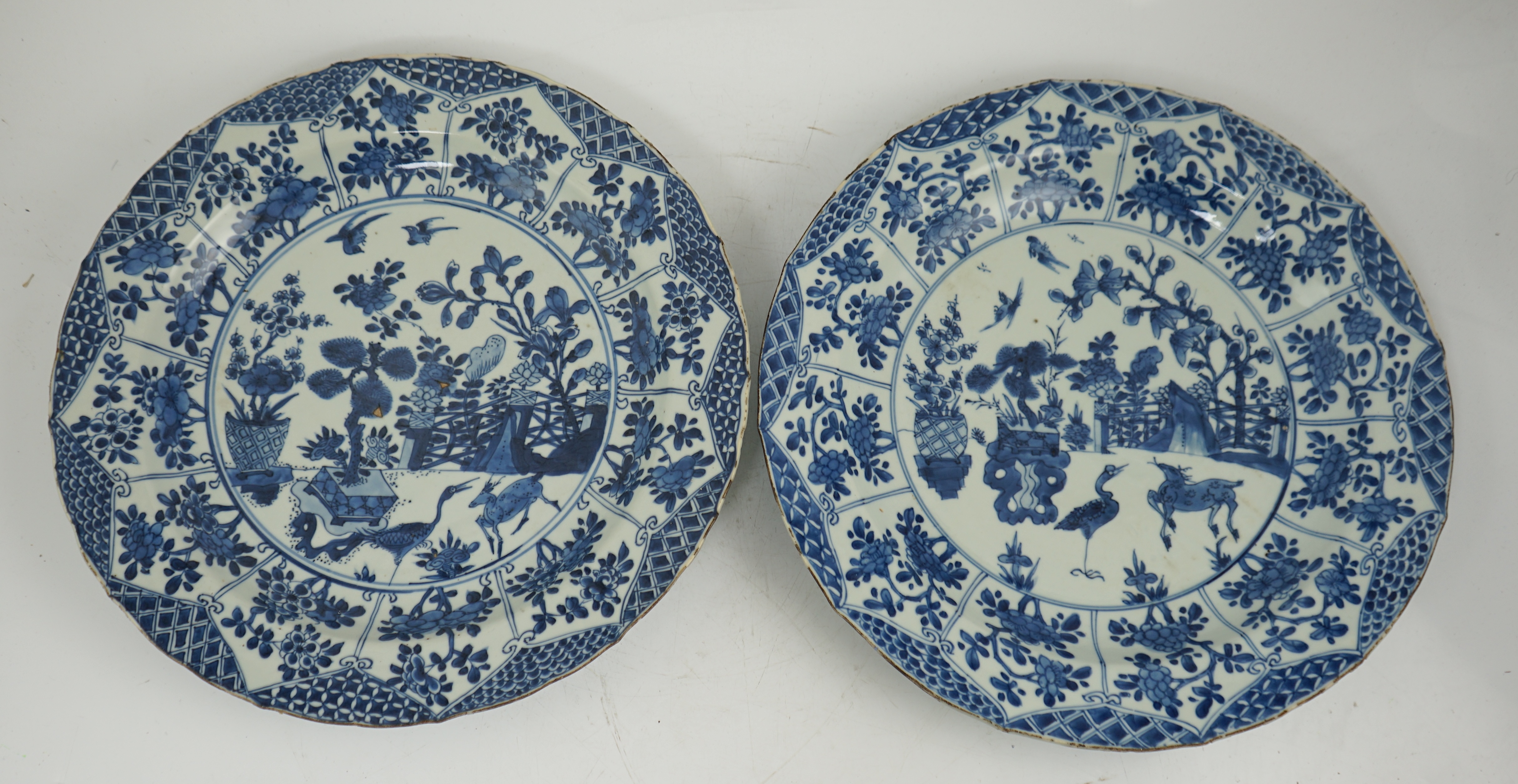 A pair of Chinese blue and white ‘garden’ dishes, Kangxi period, fritting and glaze chips